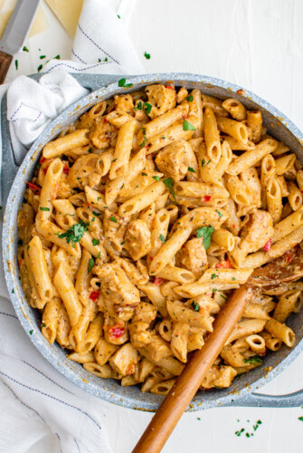 A pot of creamy pasta with chicken and peppers.