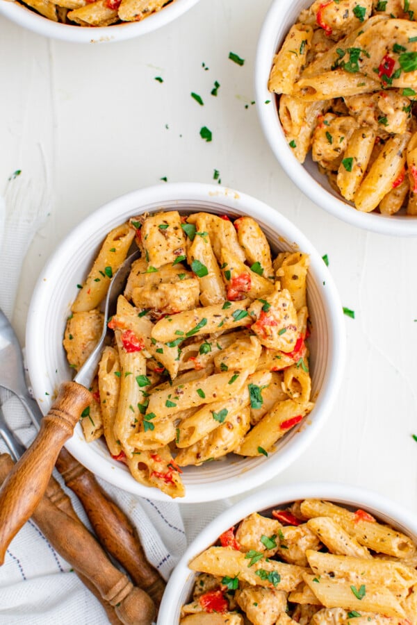 A bowl of chicken and penne with parsley.
