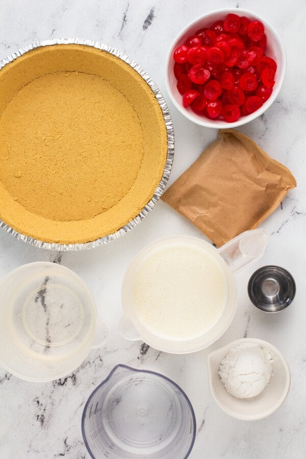 Ingredients for a cherry pie in bowls on a marble counter top. 