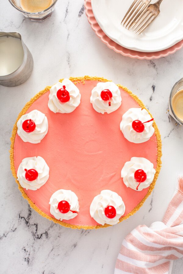 Overhead image of cherry jello pie with whip cream and cherries on top. 