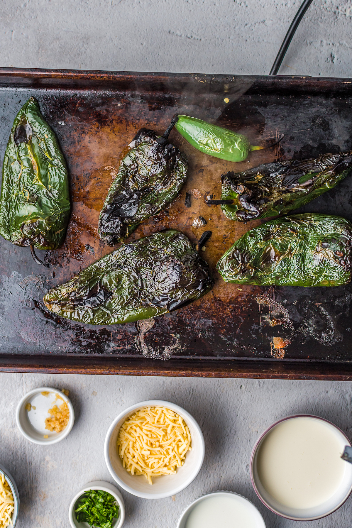 Roasted poblano peppers on a cutting board.