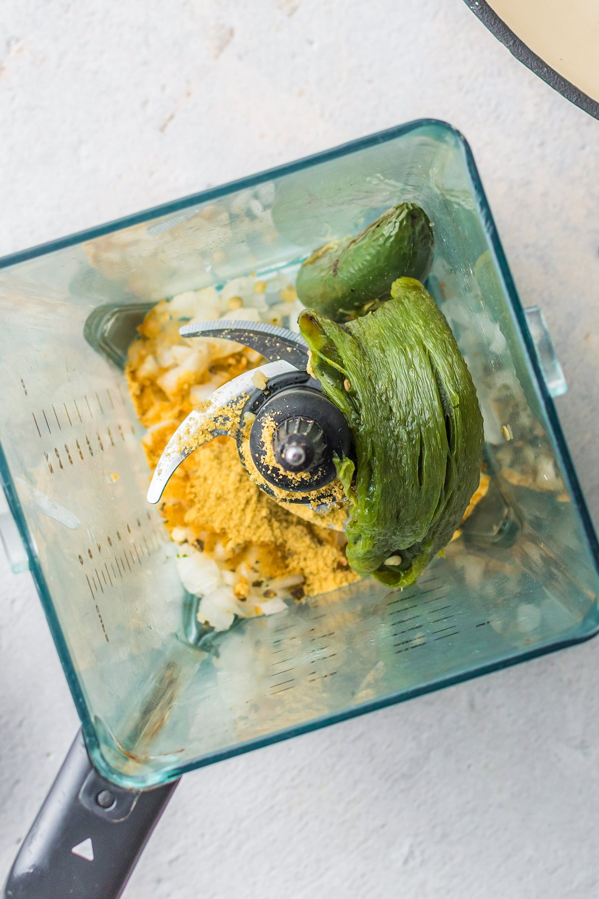 A poblano pepper with seasoning in a blender.