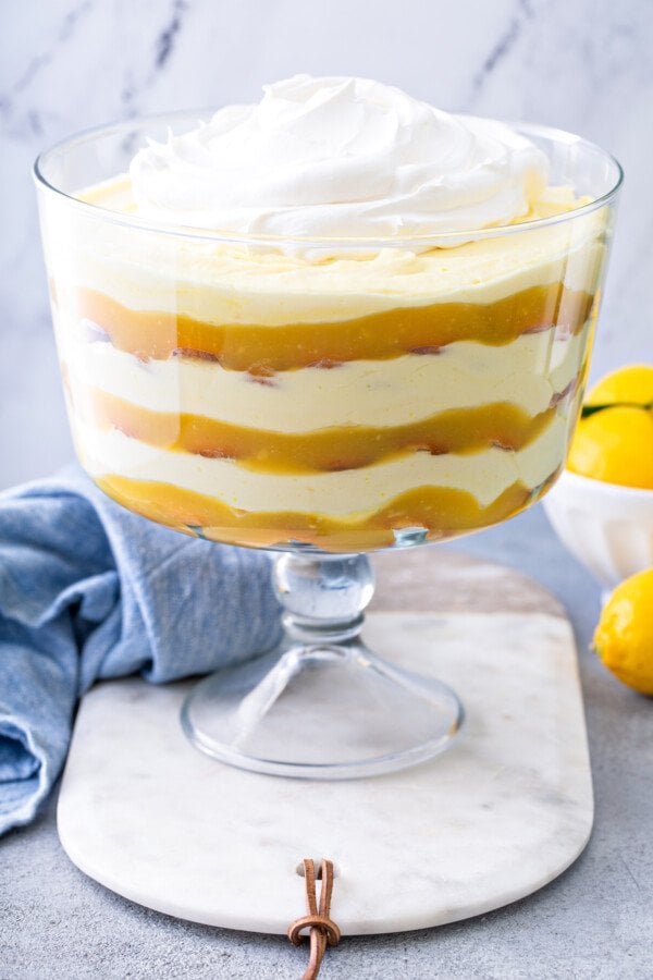 Side view of a trifle with lemon pudding and vanilla wafer cookies with whip cream on top.