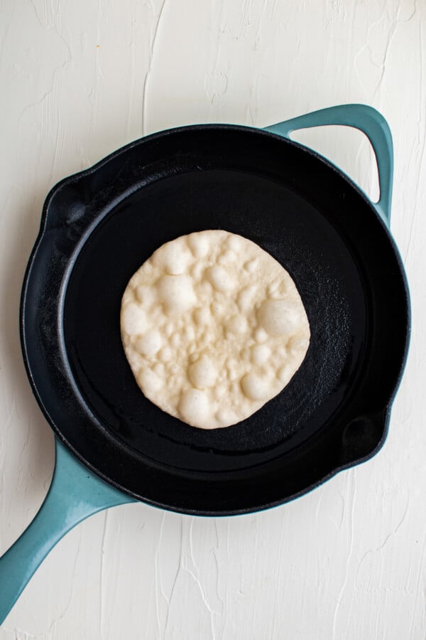 Half-cooked pita bread in a skillet.