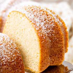 A slice of vanilla pound cake is being pulled away with a cake server.