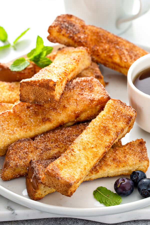 A stack of French toast sticks is on a white plate. 