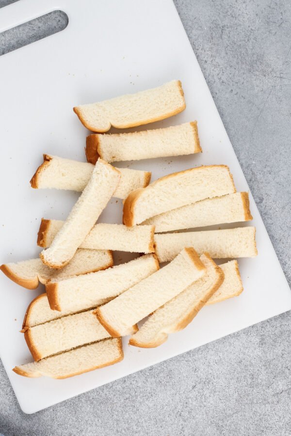 Sliced white bread is placed on a cutting board. 