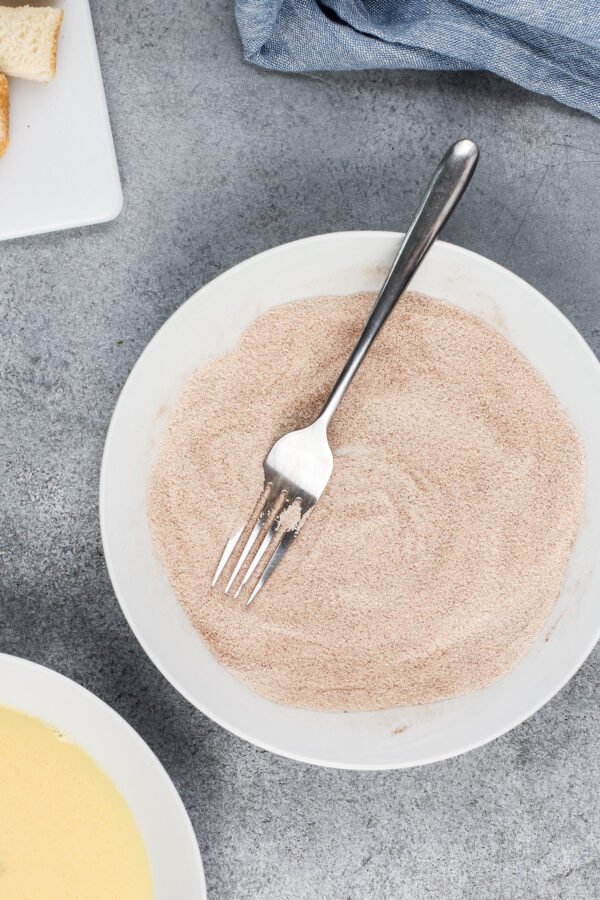 Cinnamon sugar is in a white bowl with a fork. 