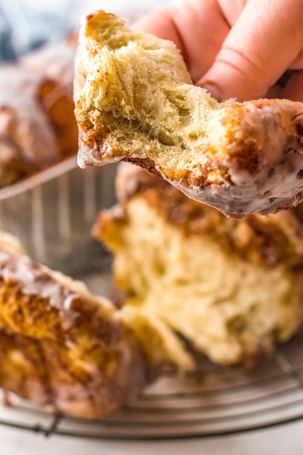 Pulled apart cinnamon bread being pulled apart with a hand with a bite taken out of it. 