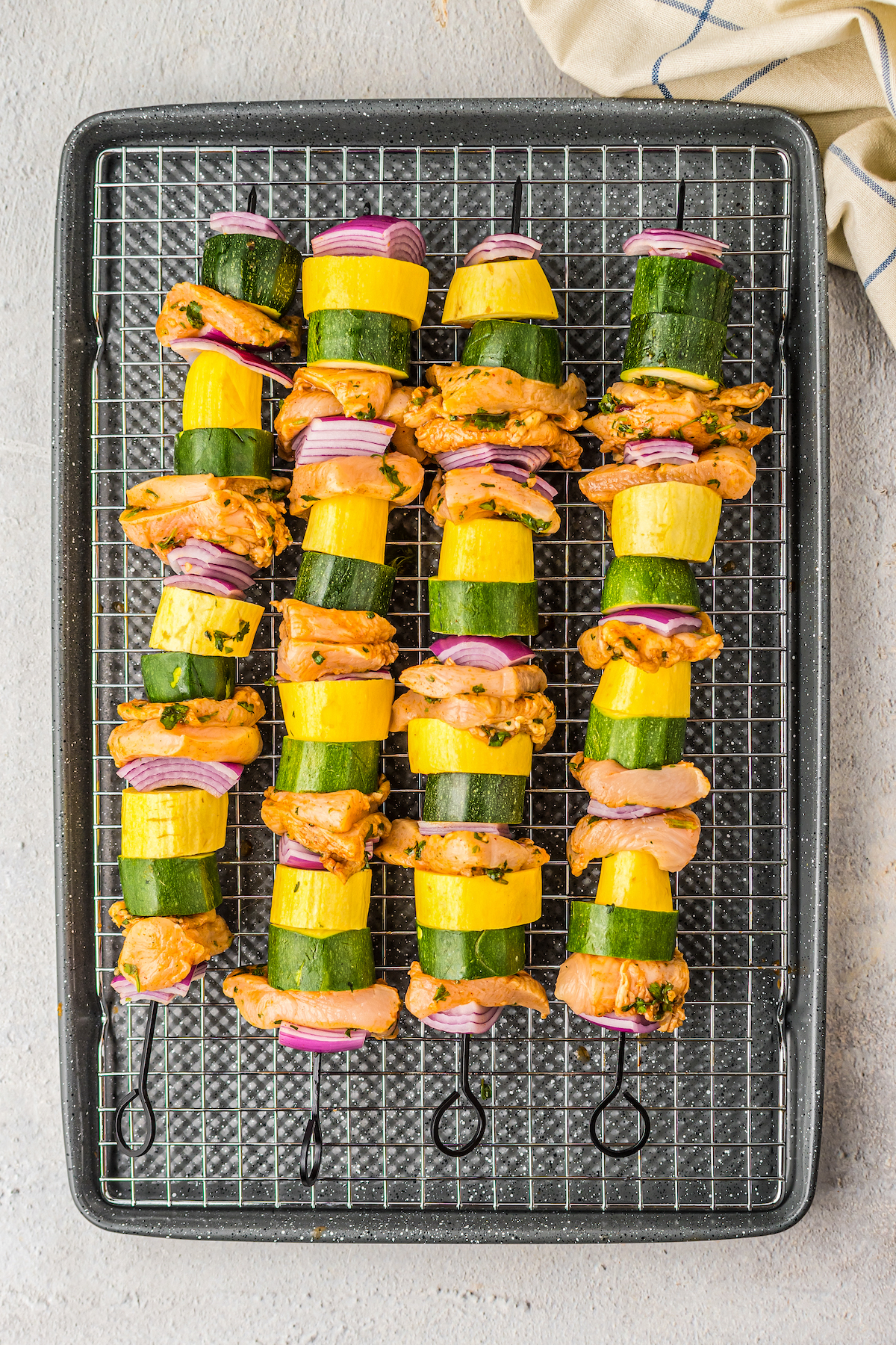 Un-grilled chicken kabobs on a tray.