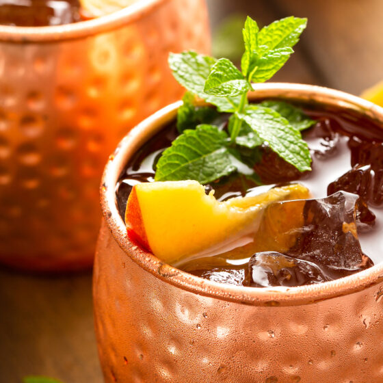 Two copper mugs are garnished and filled to the brim.