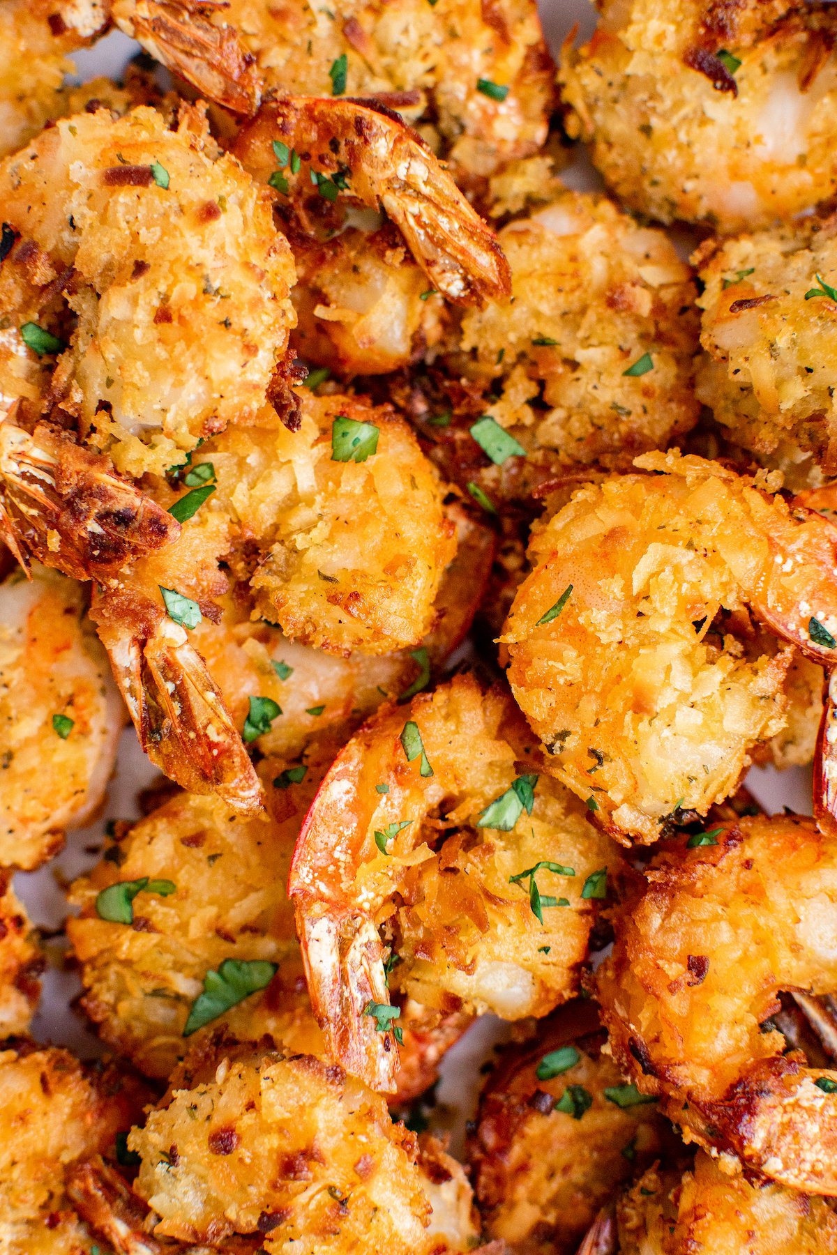 Slightly sweet and juicy air fryer coconut shrimp with a golden brown coconut coating topped with fresh parsley. 