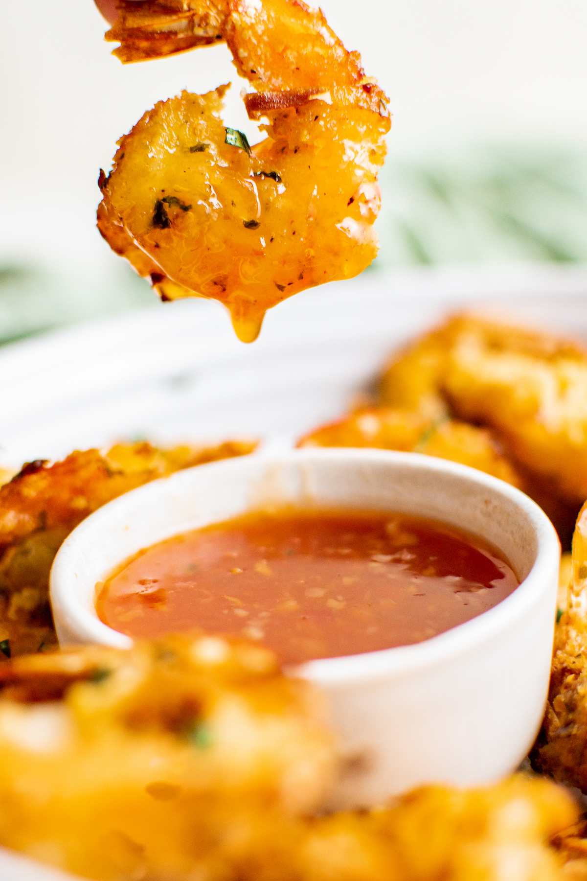 Dipping coconut shrimp in a bowl of chili sauce.