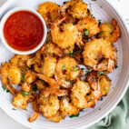 white plate of air fryer coocnut shrimp with tomato dipping sauce