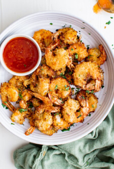 white plate of air fryer coocnut shrimp with tomato dipping sauce