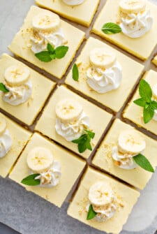Banana pudding bars are garnished with banana slices, whipped cream and mint sprigs.