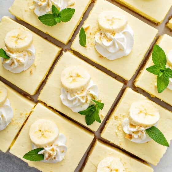 Banana pudding bars are garnished with banana slices, whipped cream and mint sprigs.