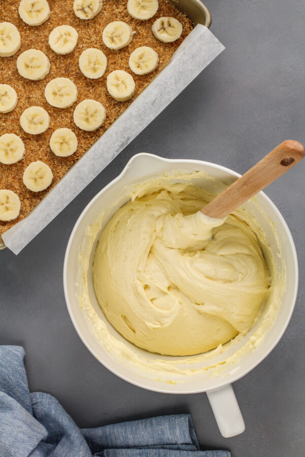 Banana pudding is mixed in a white mixing bowl. 