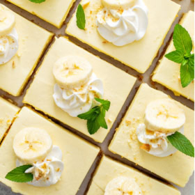 Overhead image of banana pudding bars with mint, whipped cream and banana slices on top.