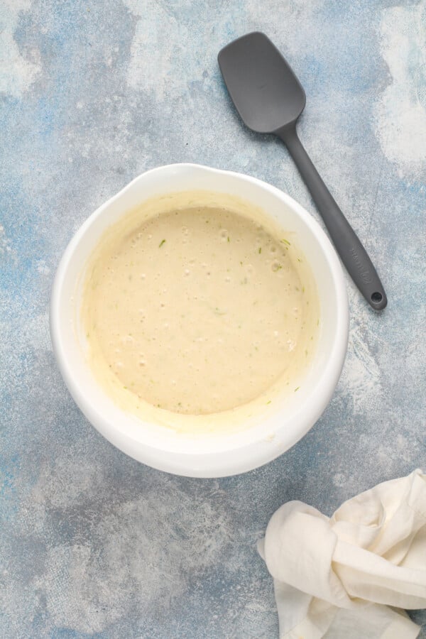 Overhead image of a white bowl with cake batter in it with a spatula on the side.