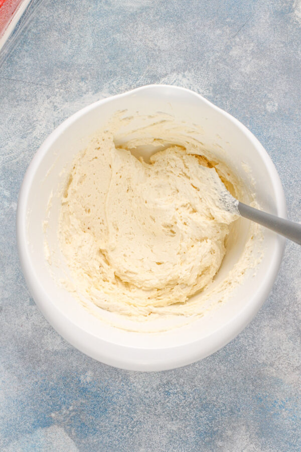 Overhead image of a white bowl with cream cheese whipped frosting inside.