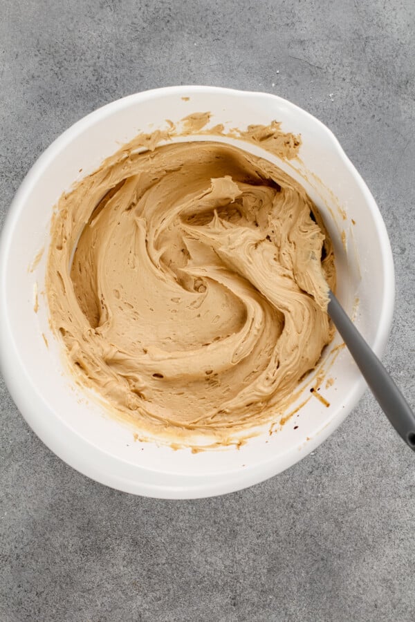 Buttercream is being mixed in a white bowl. 