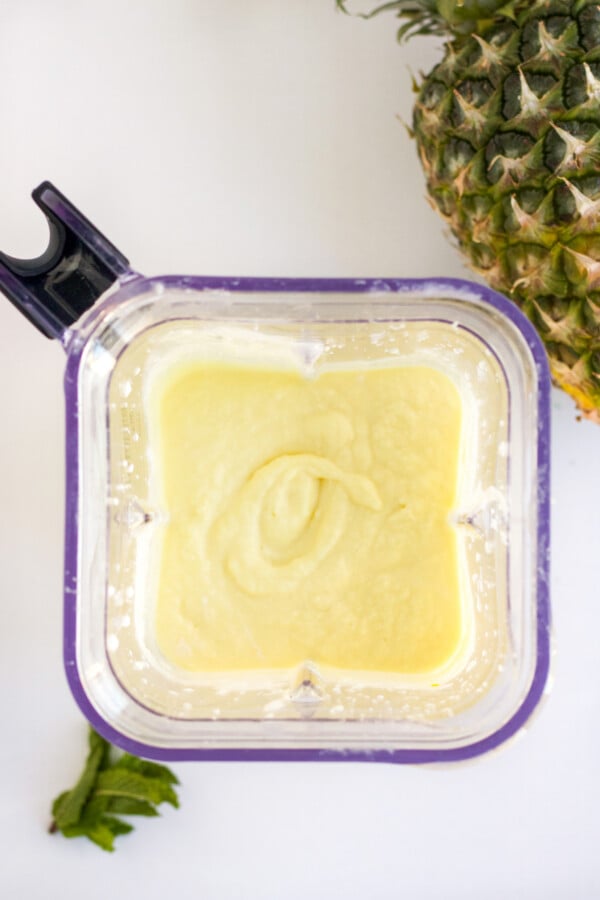 overhead of a blender with pineapple puree for popsicles