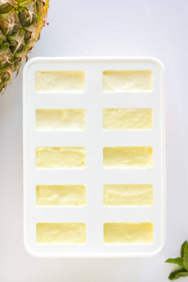 filled popsicle mold with pineapple mixture