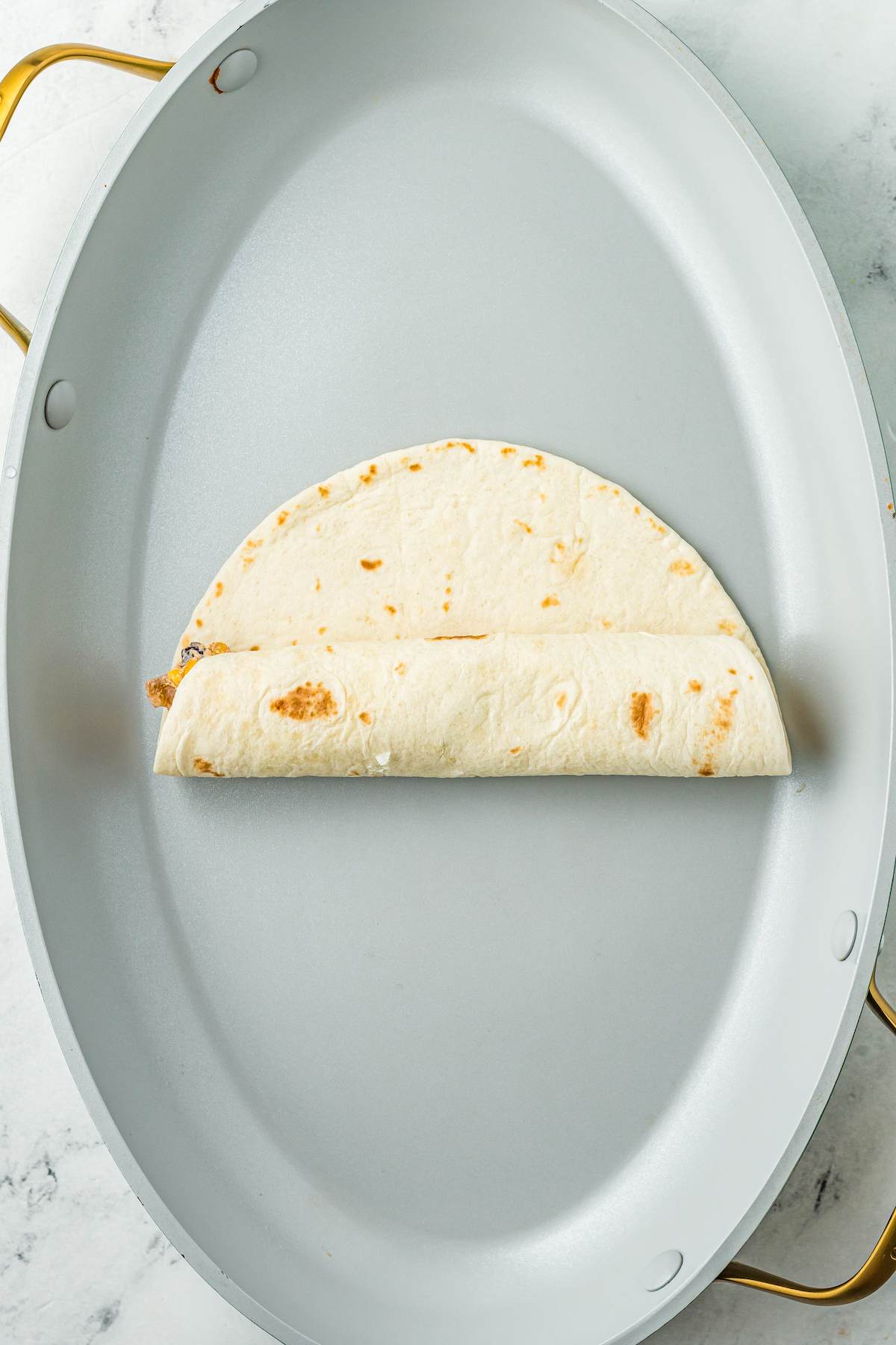 A tortilla being rolled up on a plate.