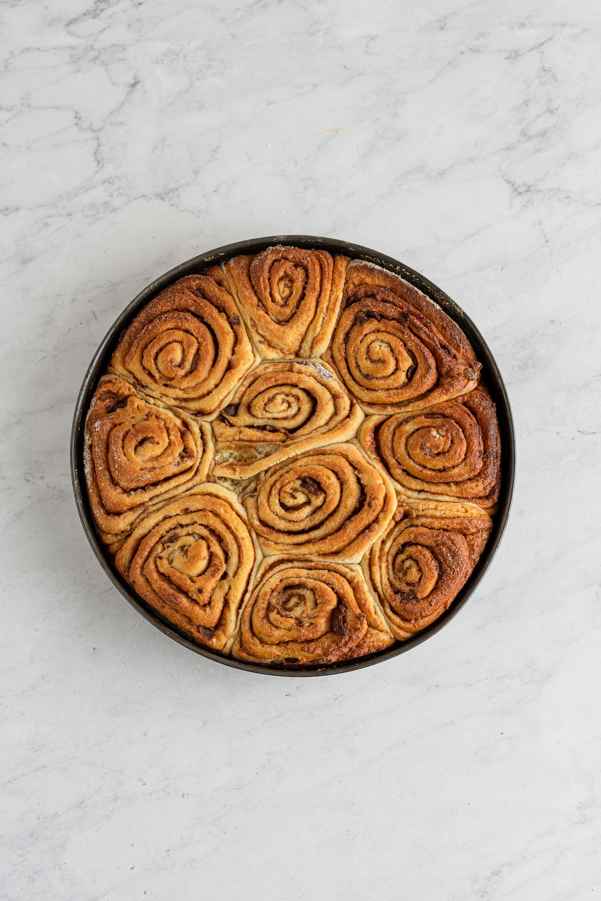 Baked, golden-brown cinnamon rolls in a pan.