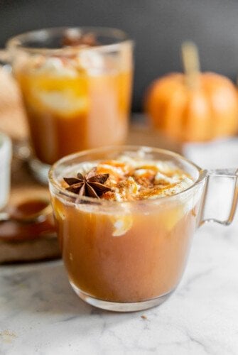 A cup of apple cider with whipped cream and star anise.