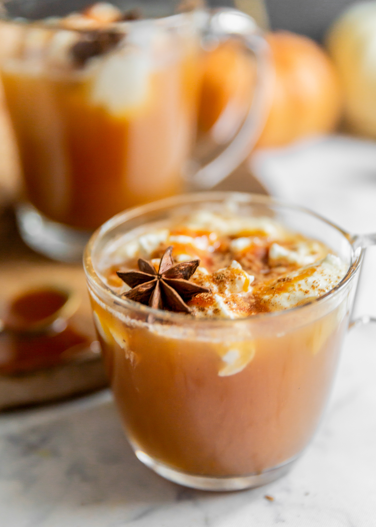 A glass of warm cider with caramel sauce.