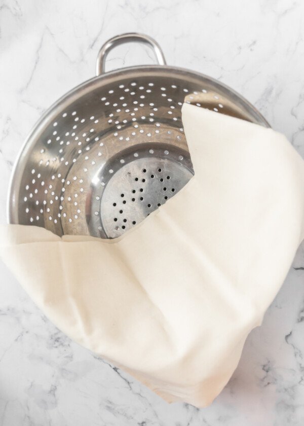 A strainer with a cheesecloth in it.