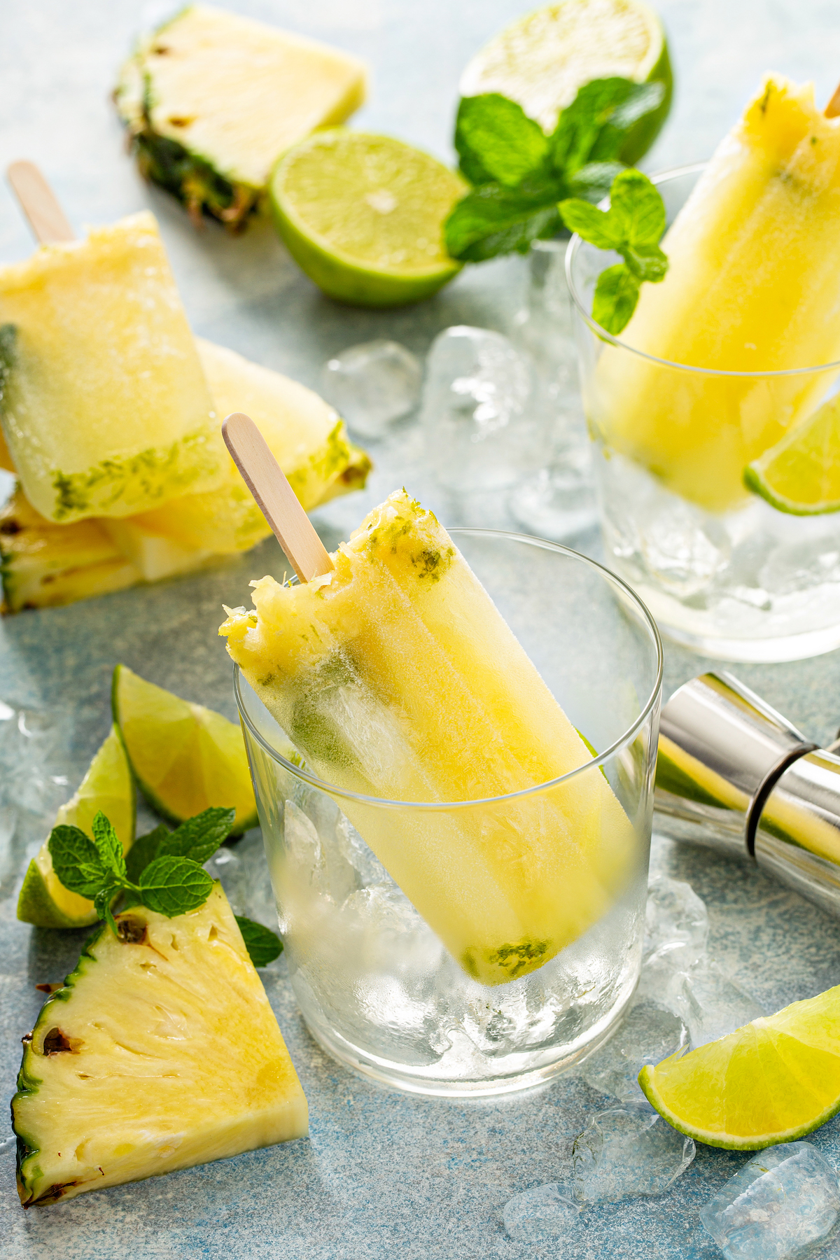 Pineapple Mojito Popsicles in glass jars with ice and lime. 
