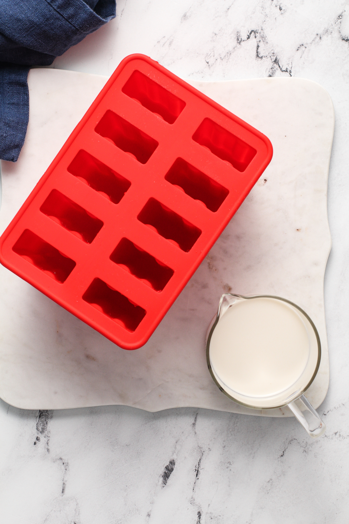 popsicle mold with oatmilk in a measuring cup