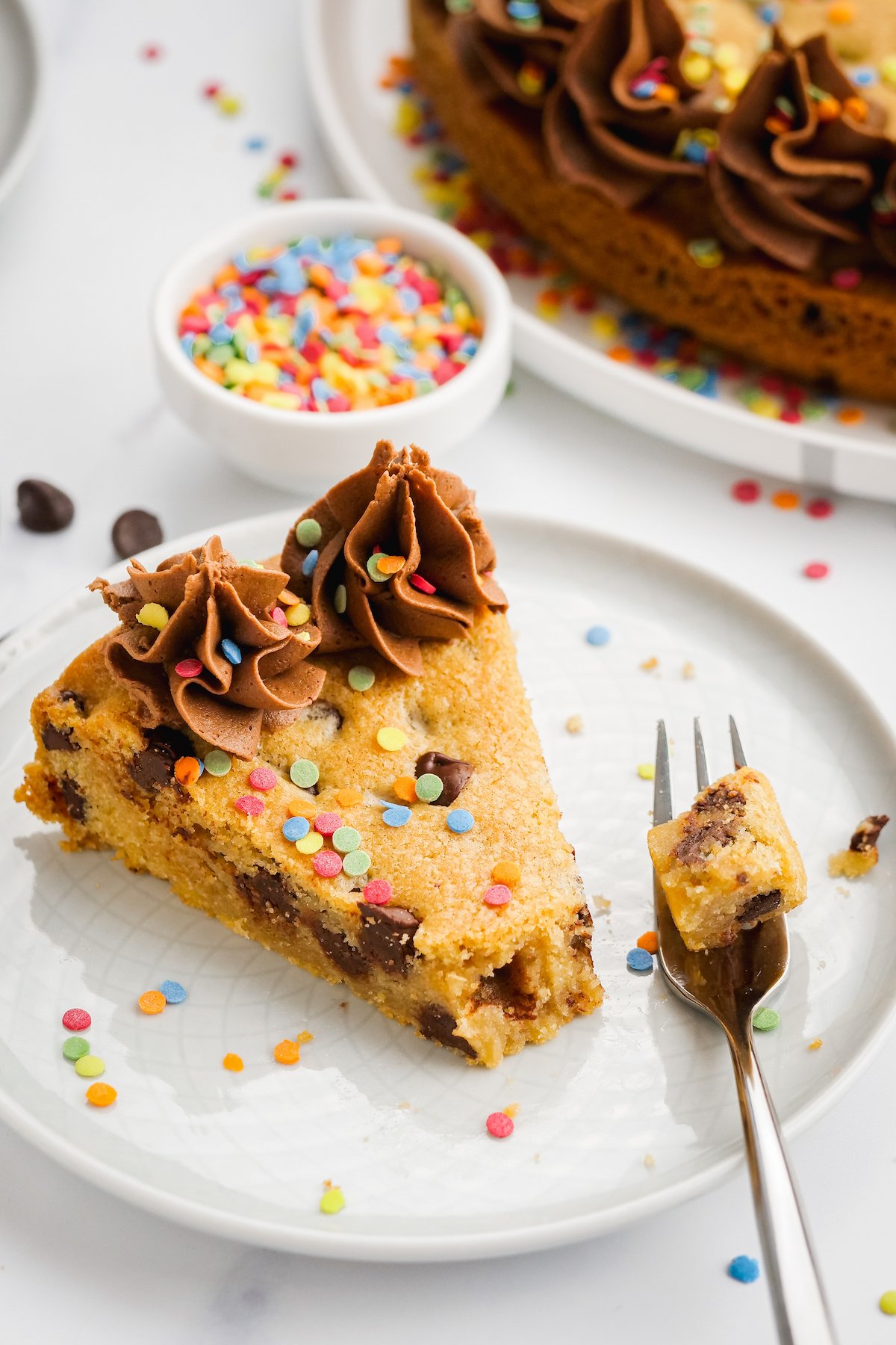 Slice of chocolate chip cookie cake on a plate.