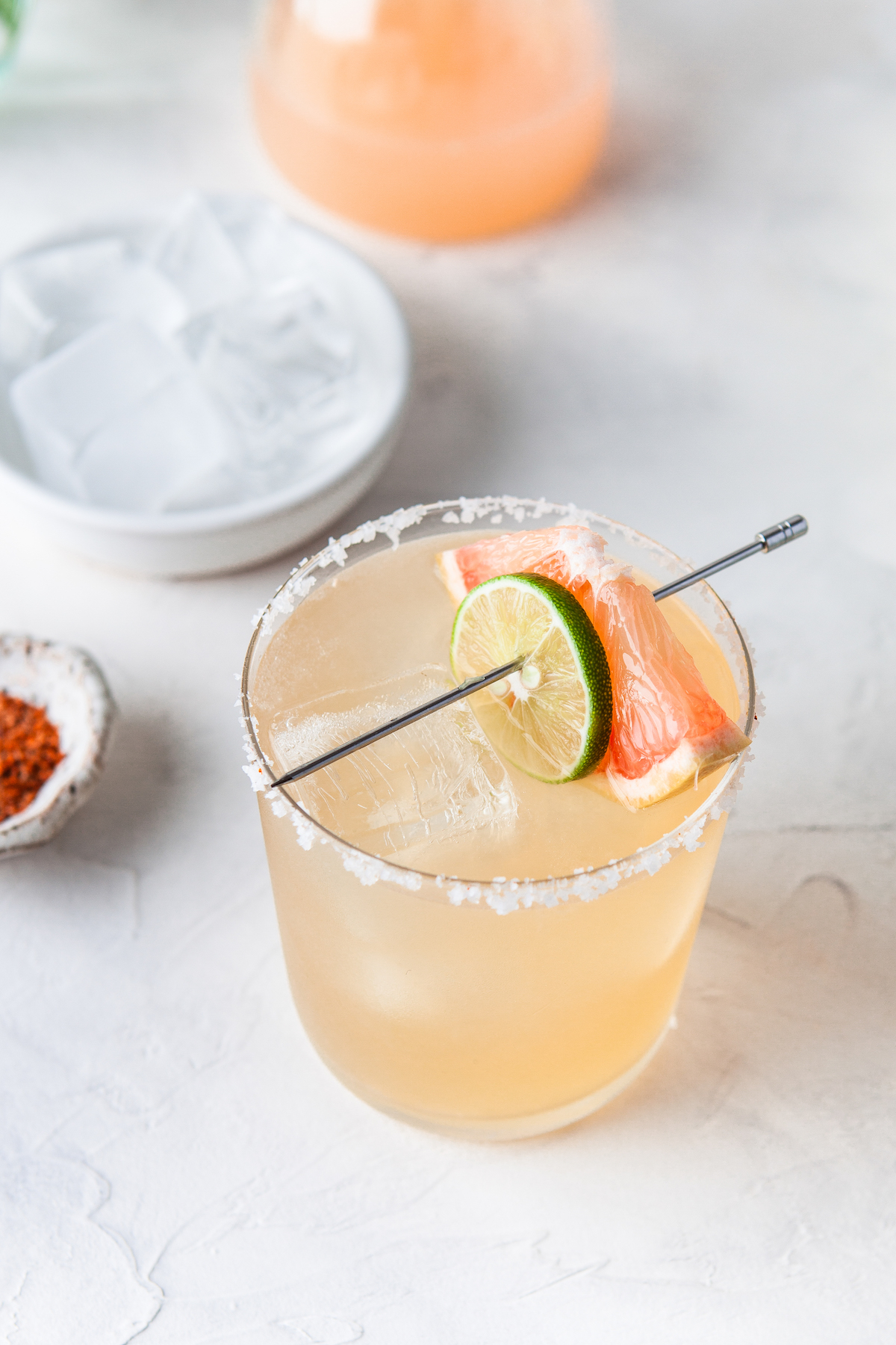 A grapefruit paloma with a lime wedge and grapefruit wedge.
