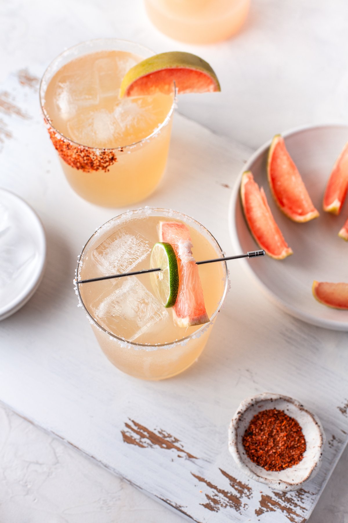 A grapefruit paloma with grapefruit and a lime wedge.
