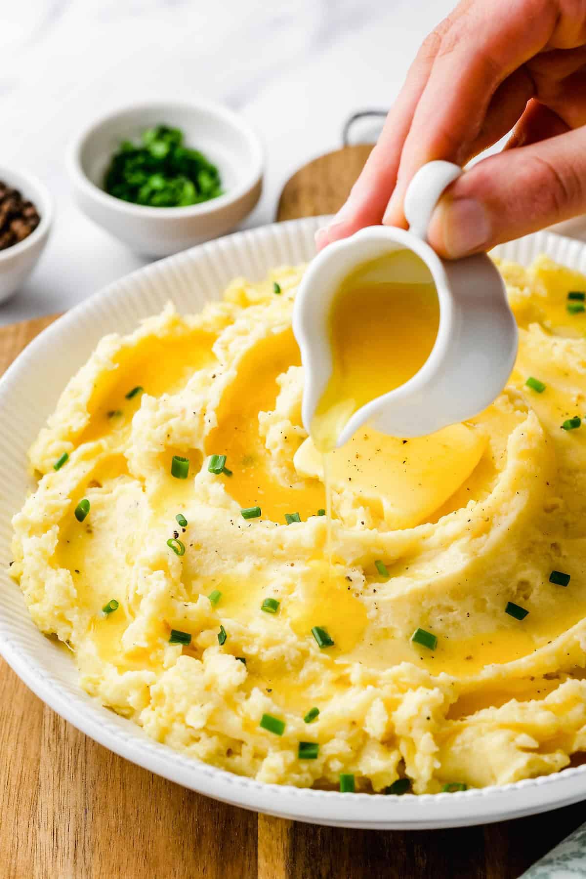 Gravy is being poured over a large portion of roasted garlic mashed potatoes.