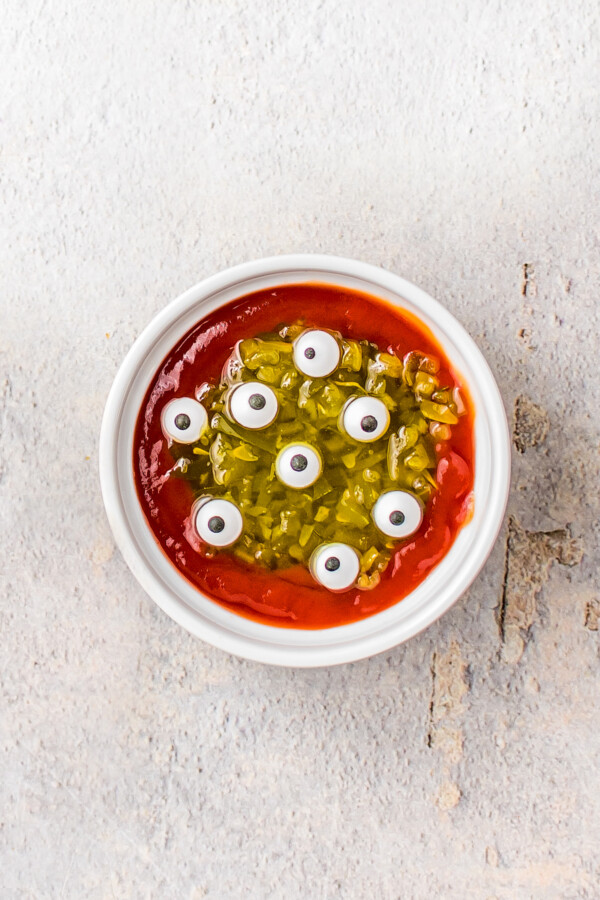 Candy eyeballs in a bowl of ketchup and relish.