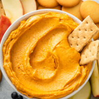 Pumpkin dip in a bowl with crackers, cookies and fruit
