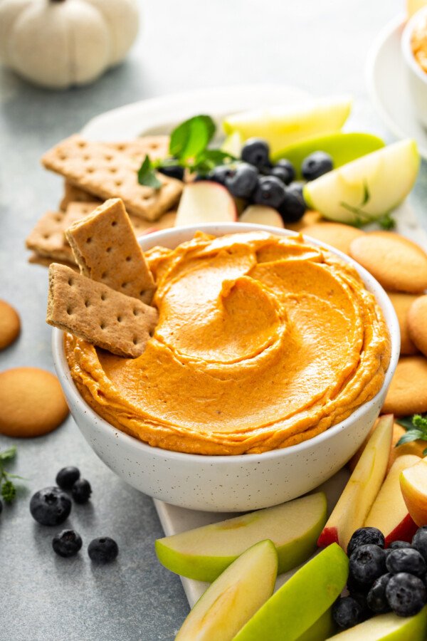 Pumpkin dip in a while bowl with graham crackers and fruit
