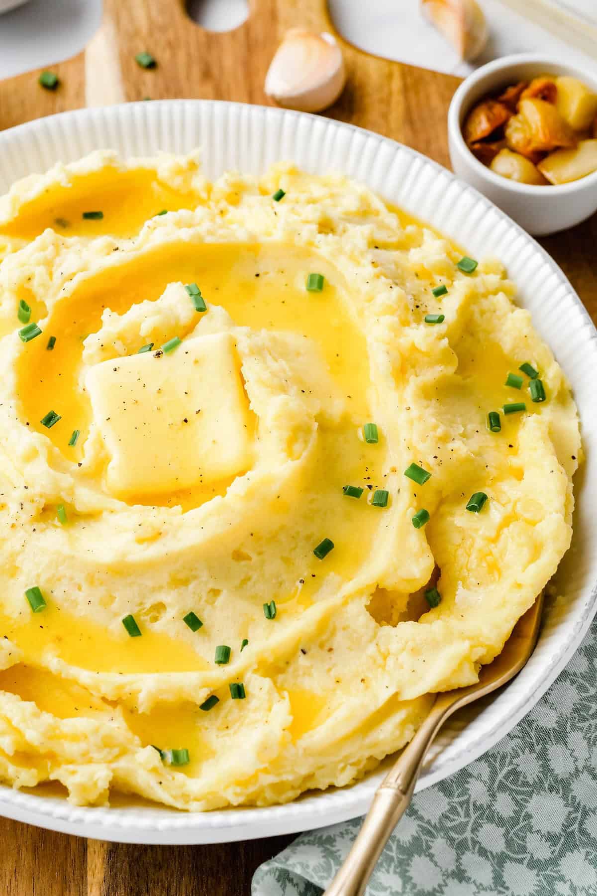 A wooden spoon is presented with a bowl of roasted garlic mashed potatoes.