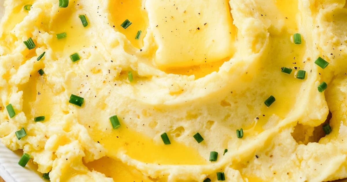 Butter, gravy, fresh herbs, and cracked black pepper top a serving of creamy garlic mashed potatoes.