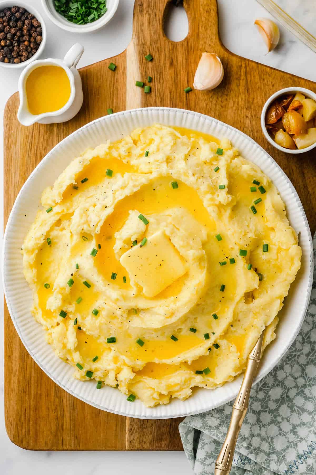 Butter and fresh herbs top a large portion of garlic mashed potatoes.