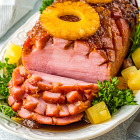 A boneless air-fryer baked ham with several serving slices cut.