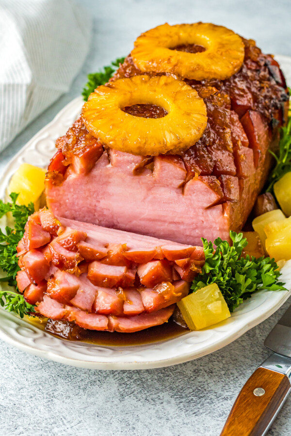 A boneless air-fryer baked ham with several serving slices cut.