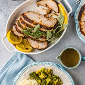 Air fryer turkey breasts sliced into pieces on a plate with sides and gravy drizzled on top.