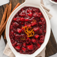 A serving dish filled with homemade cranberry apple sauce, garnished with orange zest.