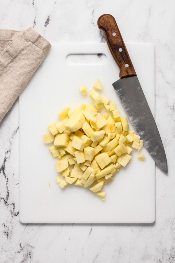 Chopped apples on a cutting board with a chef's knife.